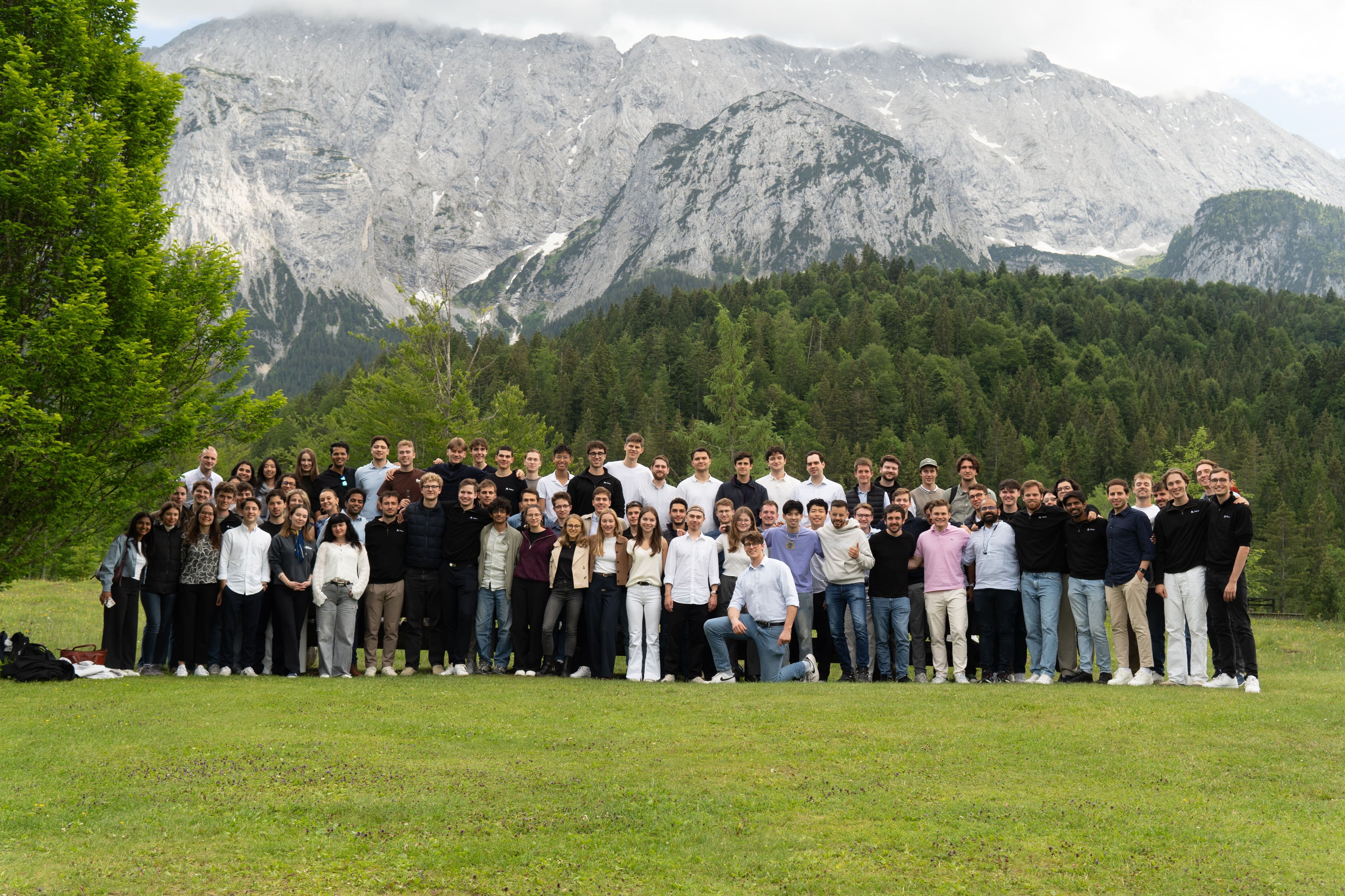 TUM.ai members and alumni in a group photo on a meadow below the Bavarian Alps